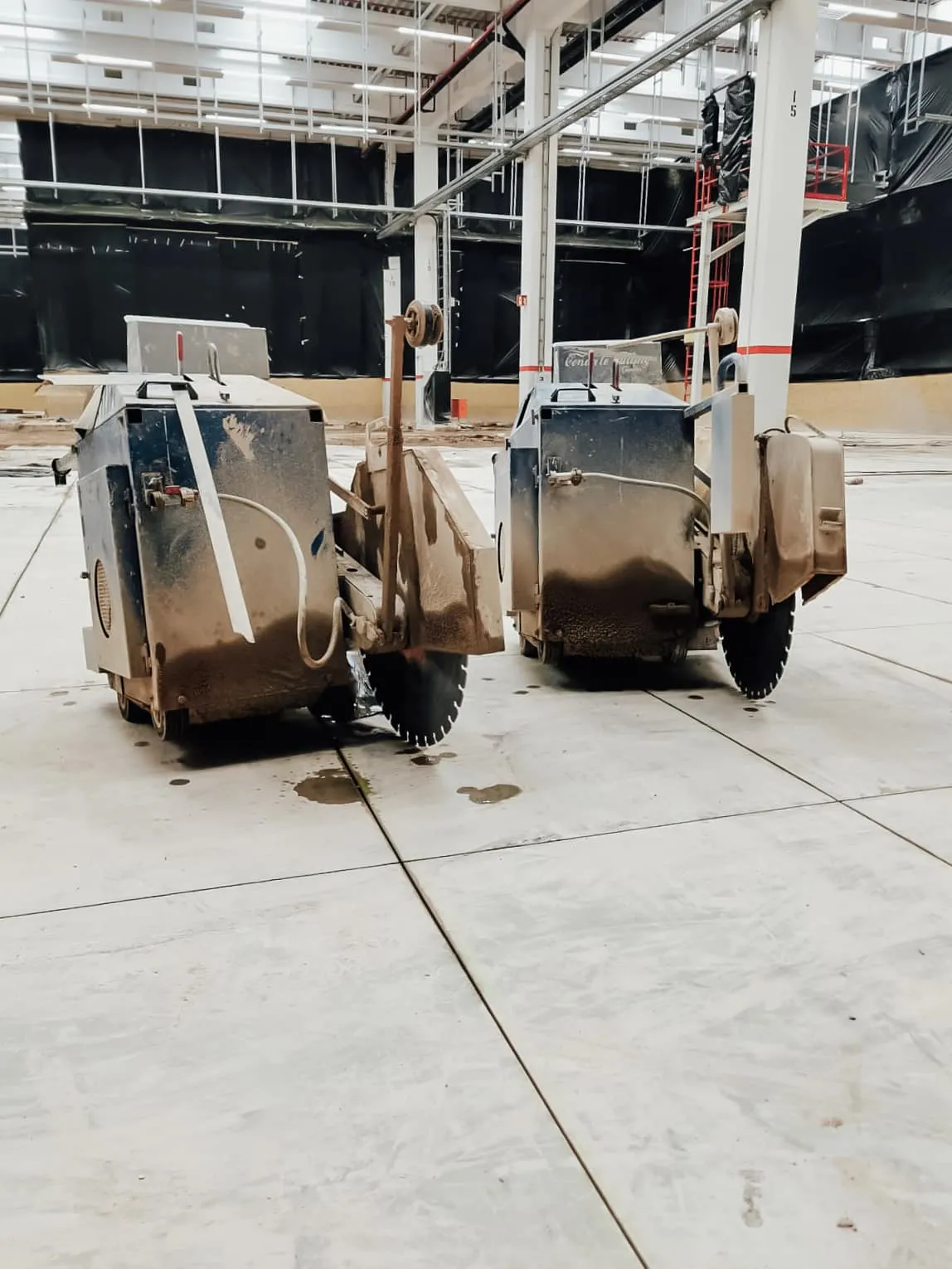 Zwei Fugenschneider stehen einsatzbereit auf einem Hallenboden aus Beton