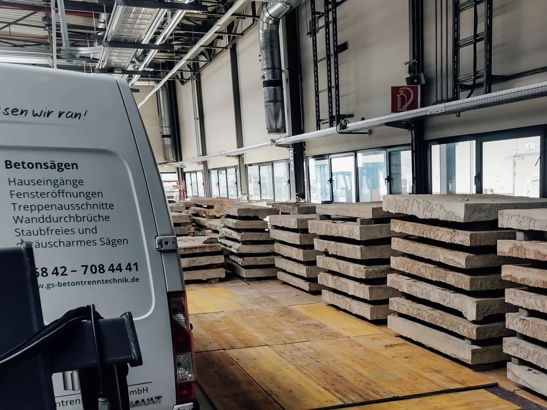 Gestapelte Betonfertigteile in einer Industriehalle mit frisch bearbeitetem Hallenboden