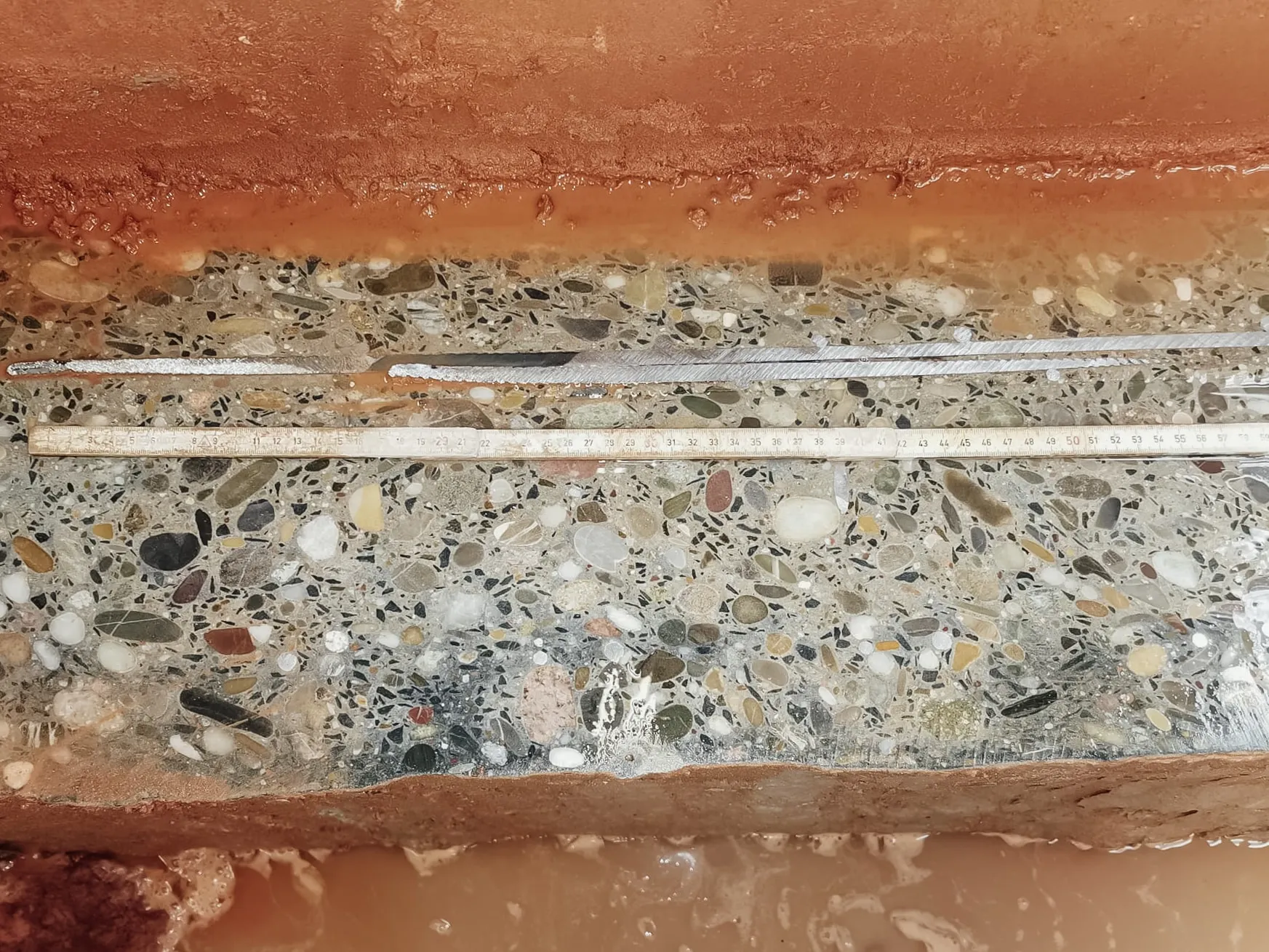 Nahaufnahme einer Betonschnittfläche mit sichtbarem Zuschlagkorn und Sägespuren